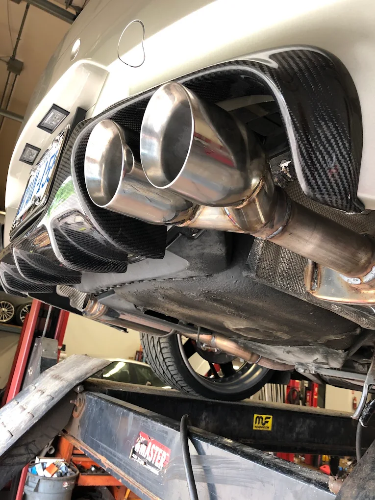 Quad polished exhaust tips exiting a carbon fibre rear diffuser on a car raised on the drive-on lift