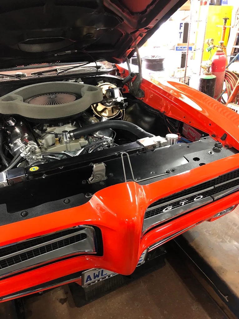 Pontiac GTO engine bay with the hood up during engine work at Pete's Muffler